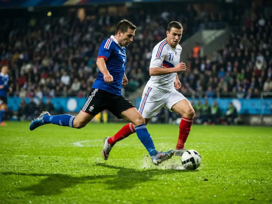 Joueurs de football en maillots nationaux lors d'un match de phase finale de Coupe du Monde sous les projecteurs du stade
